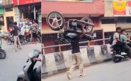Hapur youth walks on busy road carrying bike on shoulder for reel